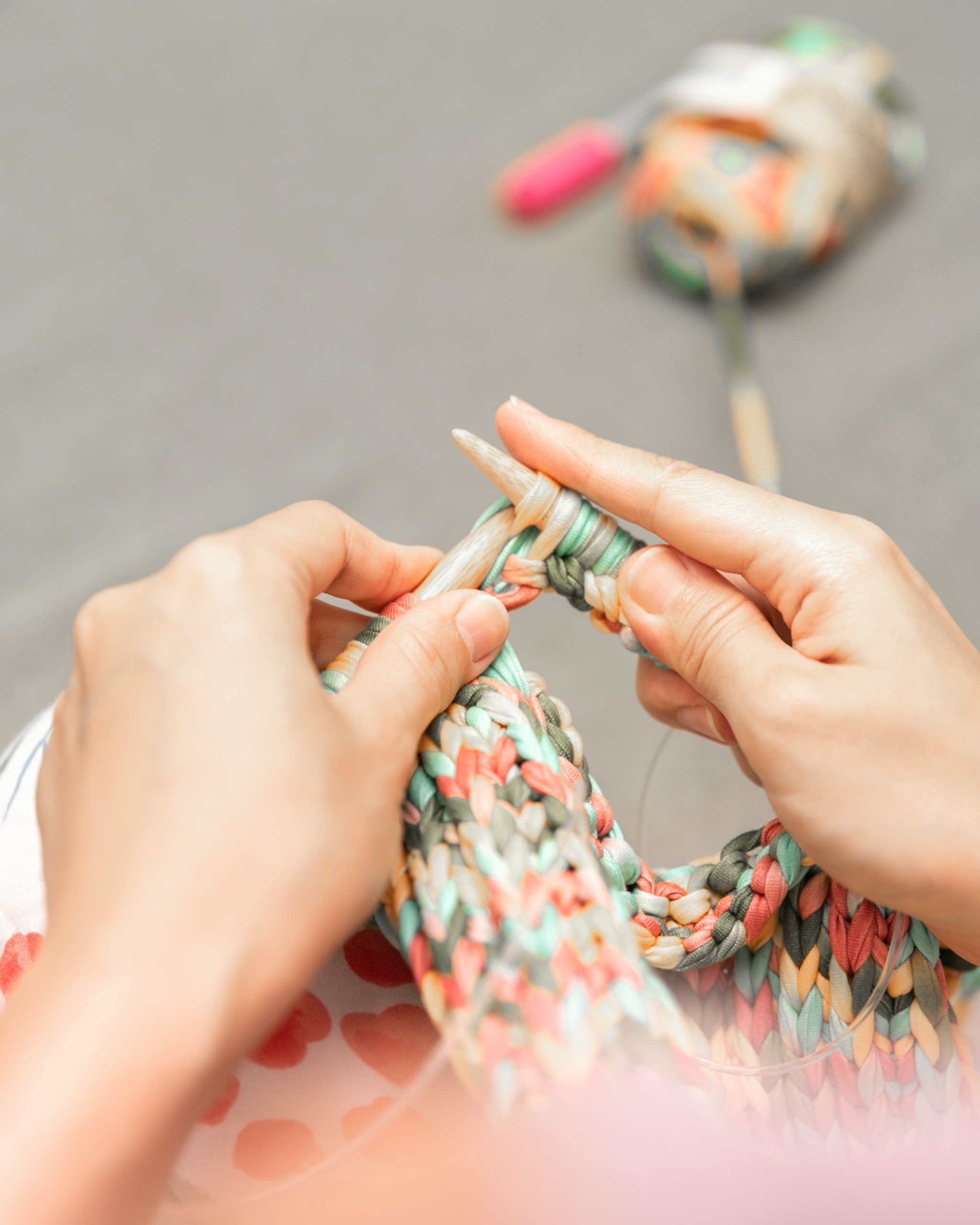 woman knitting on large needles with very colorful yarn
